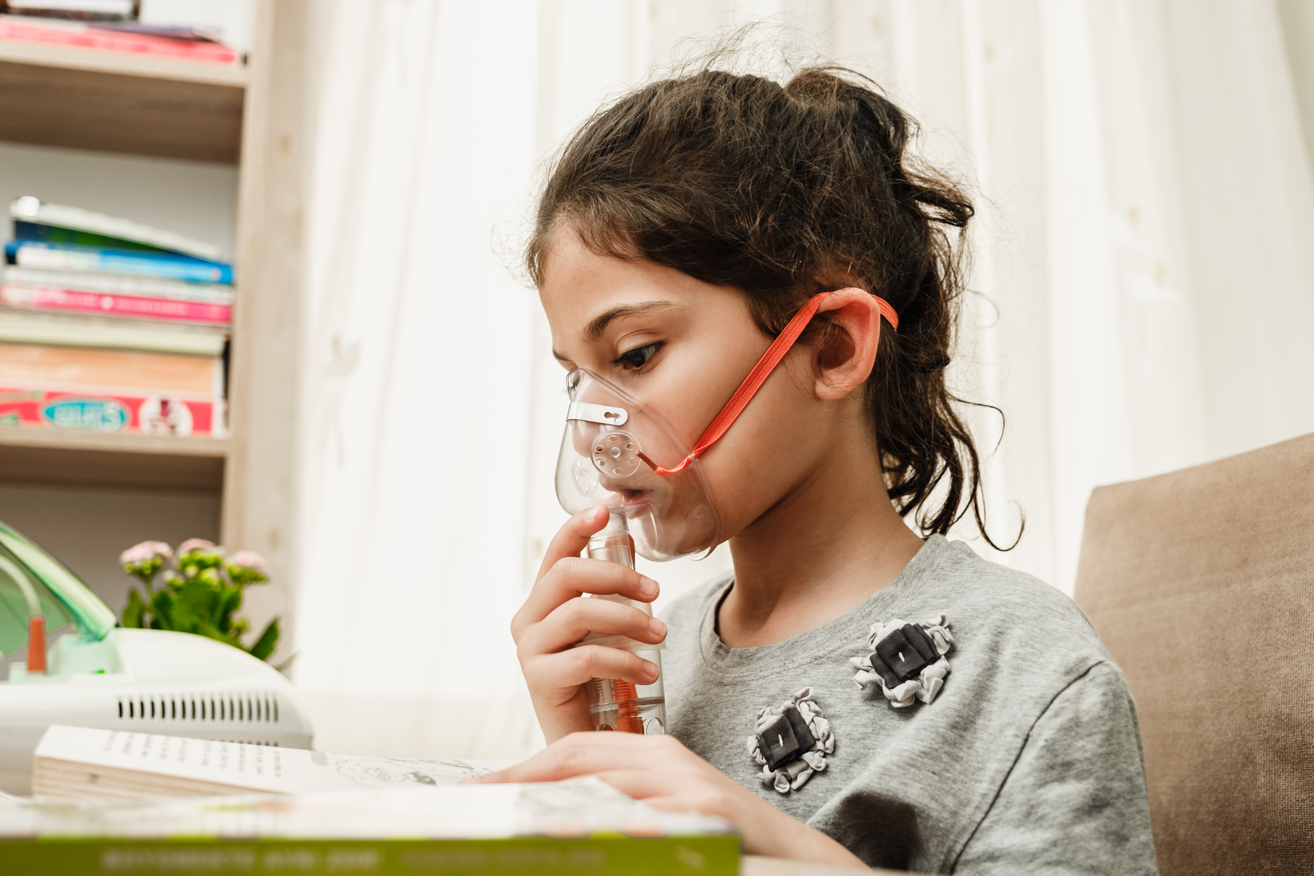 child using nebulizer while reading book