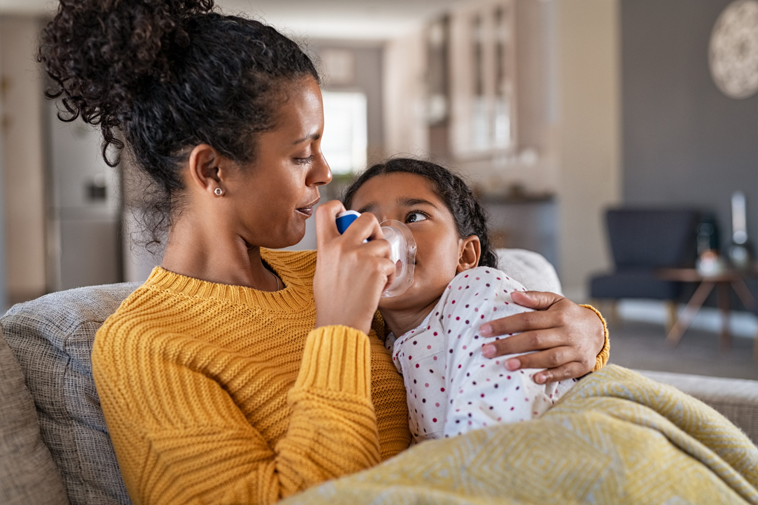 Mother administering nebulizer to daughter