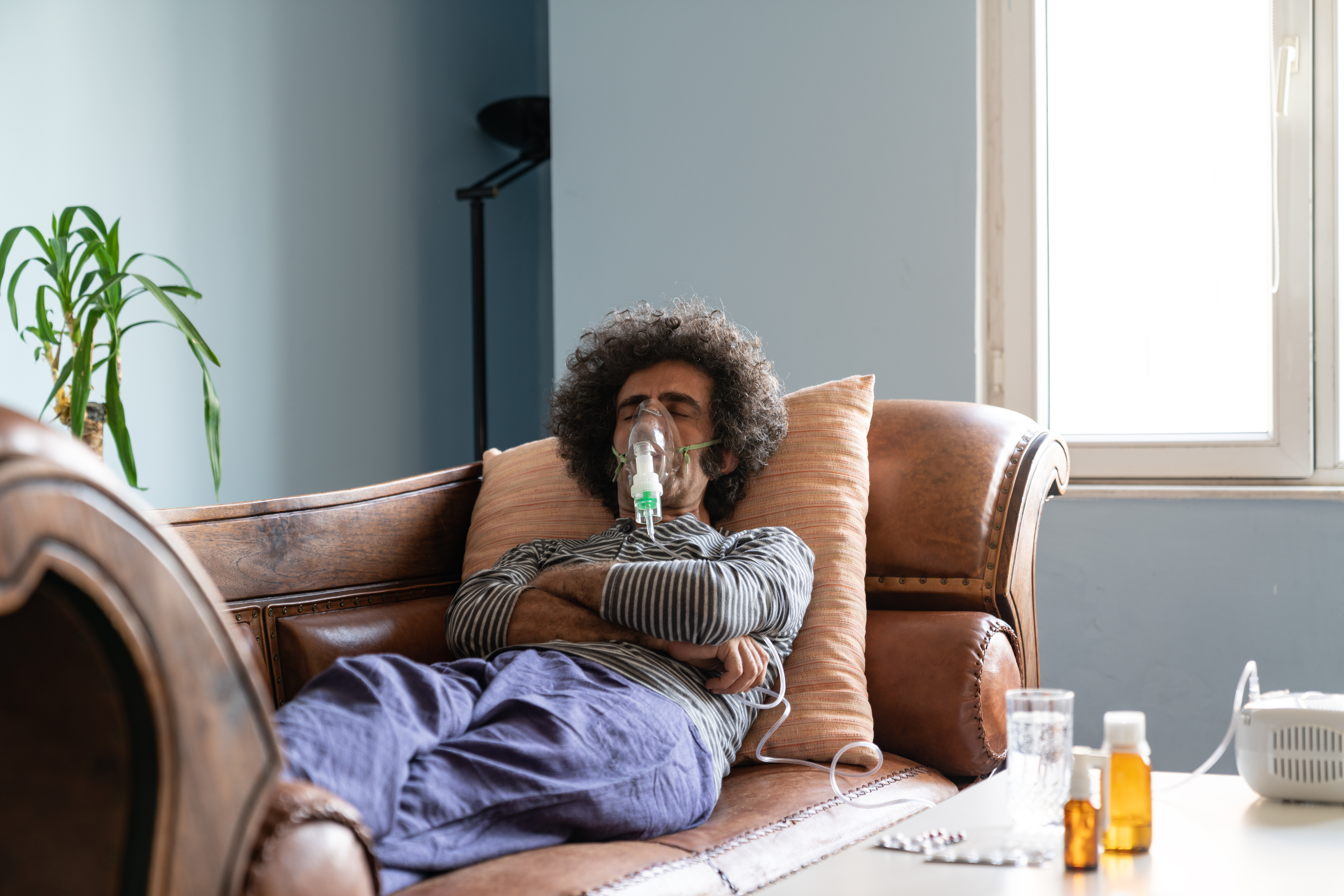 Man lying down on a couch using nebulizer