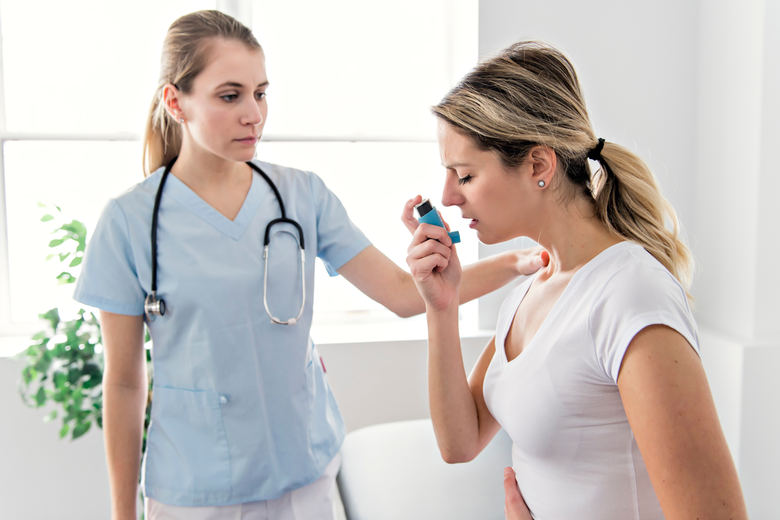 Woman using inhaler with nurse present