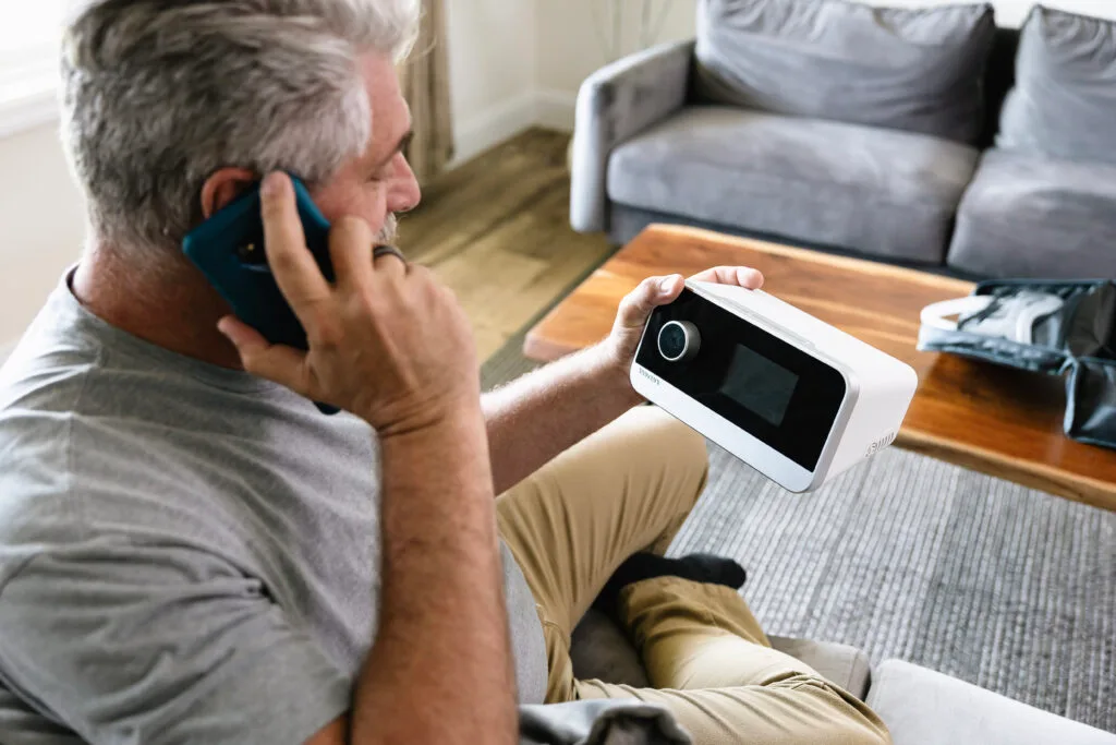 Man on the phone looking at cpap machine